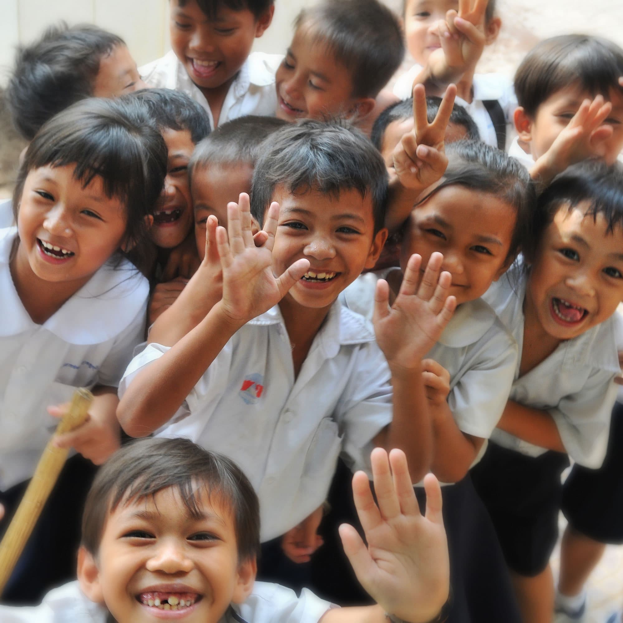 Smiling small children waving their hands.